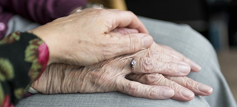 dettaglio della mano di una donna sopra quella di una persona più anziana 