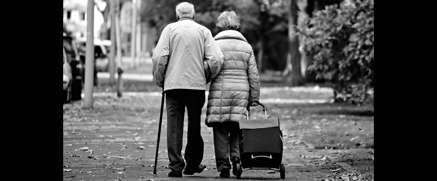 coppia di anziani di spalle mentre camminano su un marciapiede
