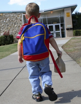 bambino con zaino di spalle entrando a scuola 
